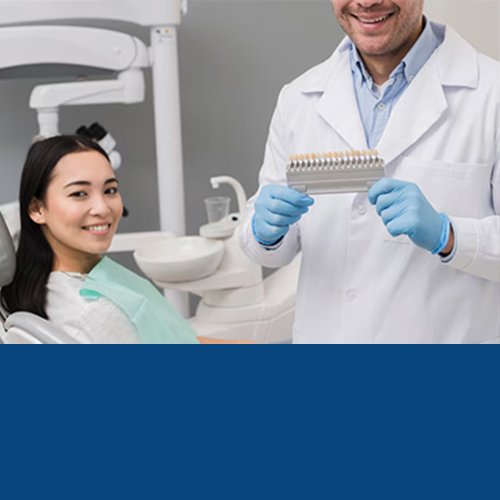Dentist in a clinic showing a dental shade guide to a smiling patient